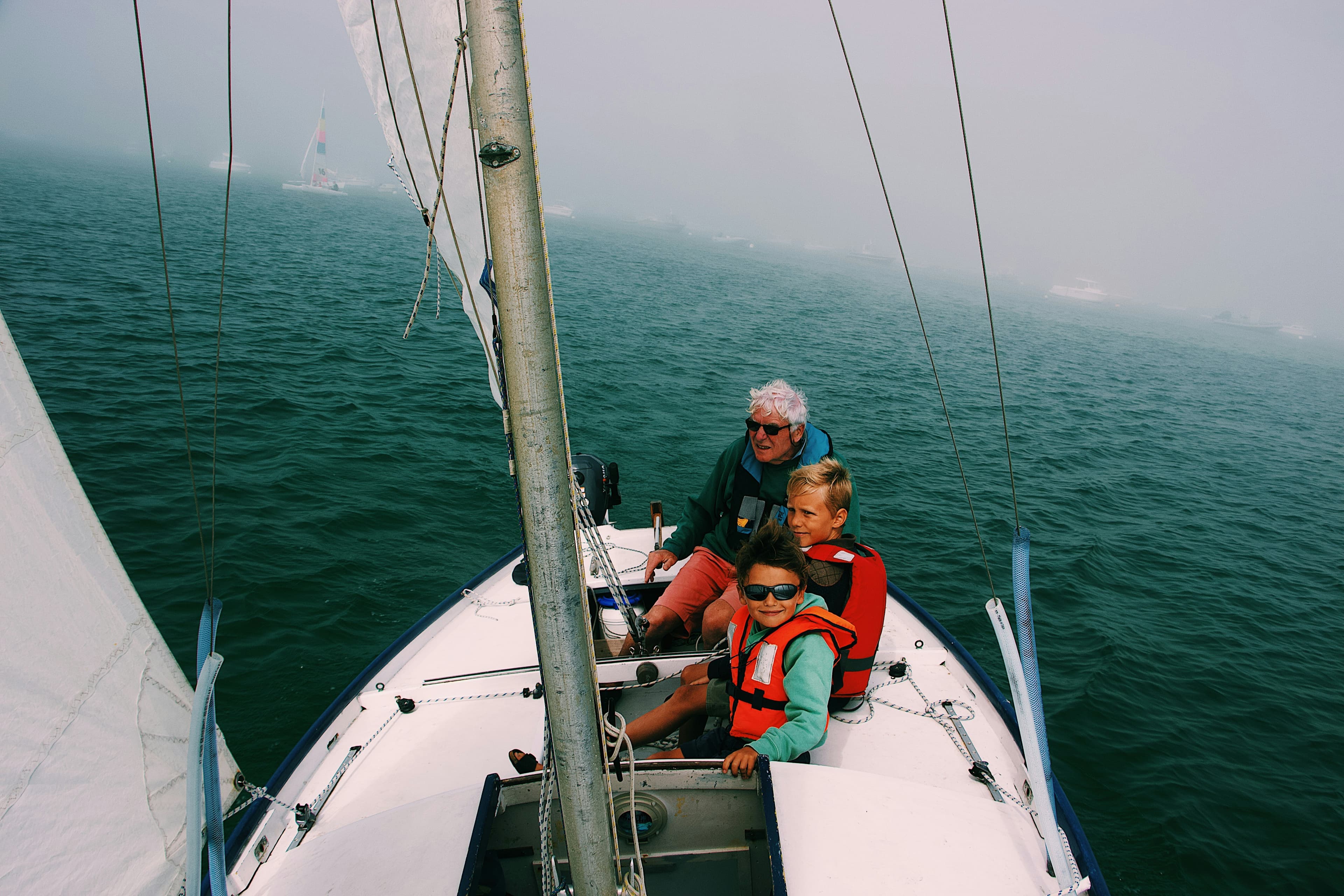 Group of people sailing together on a yacht in misty water
